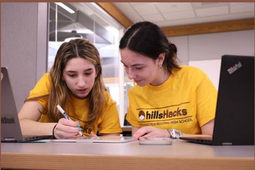 A mentor helping students at HillsHacks